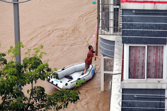  2009年7月4日，广西柳州连日暴雨，城区多条道路被淹，许多房屋被泡在水中。 一位市民划漂流艇再爬梯子回家 ...